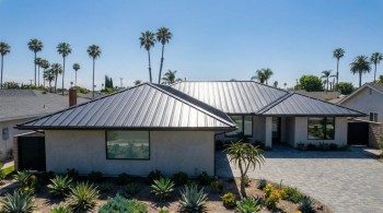 Modern suburban home with a standing seam metal roof and desert landscaping in Stanton, CA